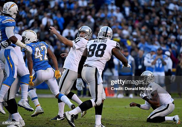 Kicker Sebastian Janikowski of the Oakland Raiders kicks the game winning field goal as punter Marquette King holds en route to the Raiders 19-16 win...