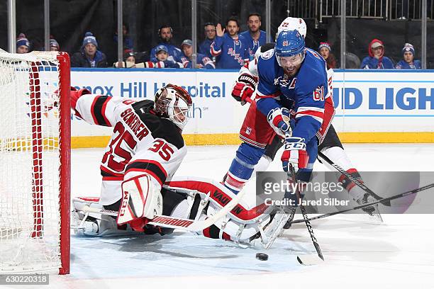 Rick Nash of the New York Rangers dekes around Corey Schneider of the New Jersey Devils but shoots the puck wide of the net in the first period at...