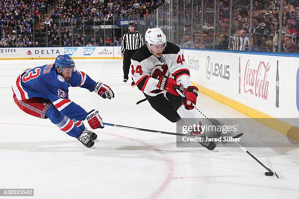 Miles Wood of the New Jersey Devils skates with the puck against Kevin Hayes of the New York Rangers at Madison Square Garden on December 18, 2016 in...