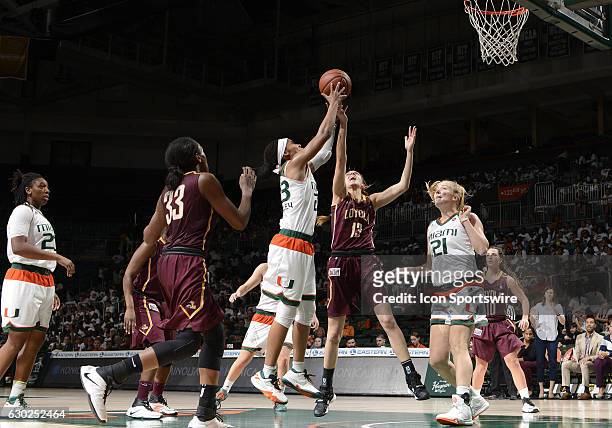 Miami guard Adrienne Motley grabs a rebound against Loyola guard/forward Katie Salmon during an NCAA basketball game between Loyola Chicago...