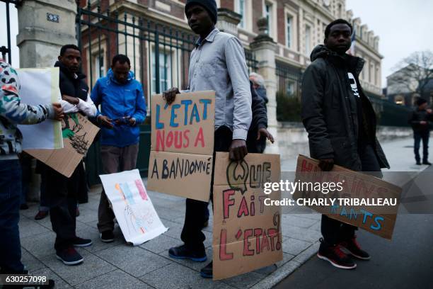 Migrant holds a placard reading 'The state has abandoned us' and 'What does the state do?' during a protest in front of the sub-prefecture in Le...