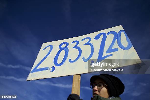 Anya Rose holds a sign with the number of votes Hillary Clinton won the popular vote, joining Donald Trump protestors demonstrating outside the...