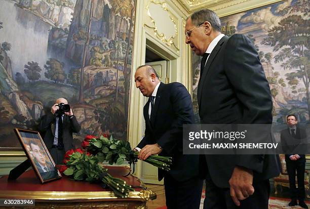 Russian Foreign Minister Sergei Lavrov and his Turkish counterpart Mevlut Cavusoglu lay flowers in front of a photo of Russian ambassador to Turkey,...