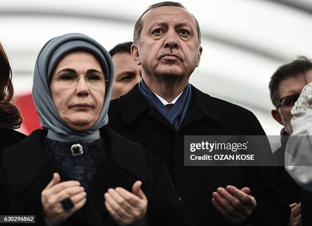 Turkish President Recep Tayyip Erdogan and his wife Emine Erdogan pray before cutting the ribbon on December 20, 2016 in Istanbul, during the opening...