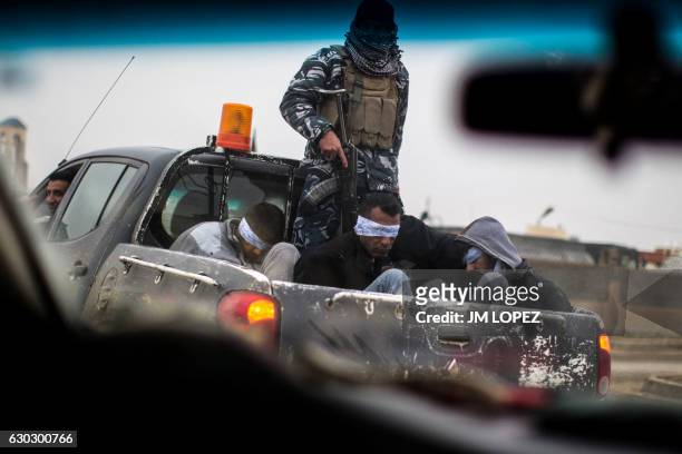 Christian militia fighters from the Nineveh Plain Protection Units drive a pick-up truck in Qaraqosh , transporting four men, allegedly members of...