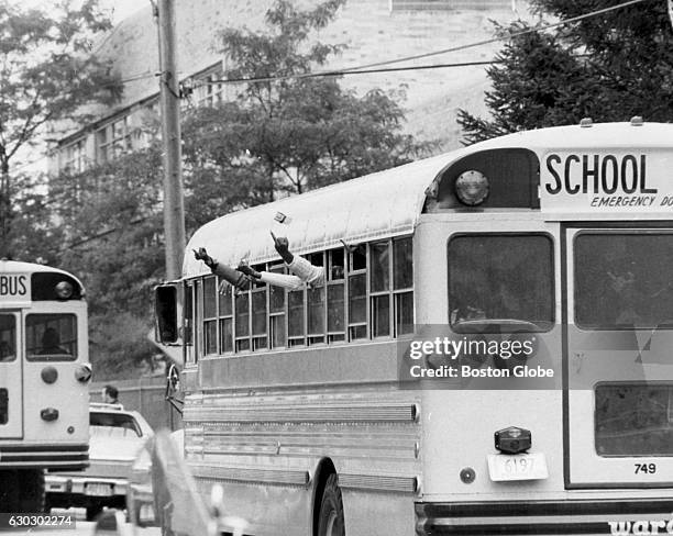 Black students stick up their middle fingers at white students from the windows of a school bus at Hyde Park High School in Boston, Mass. On Sept....