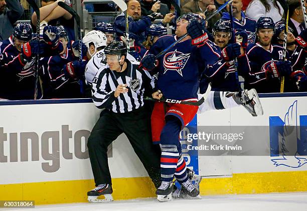 Linesman Devin Berg attempts to get out of the way as Scott Hartnell of the Columbus Blue Jackets checks Kevin Gravel of the Los Angeles Kings in the...