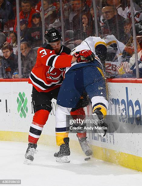 Pavel Zacha of the New Jersey Devils and Adam Pardy of the Nashville Predators battle for the puck during the game at Prudential Center on December...