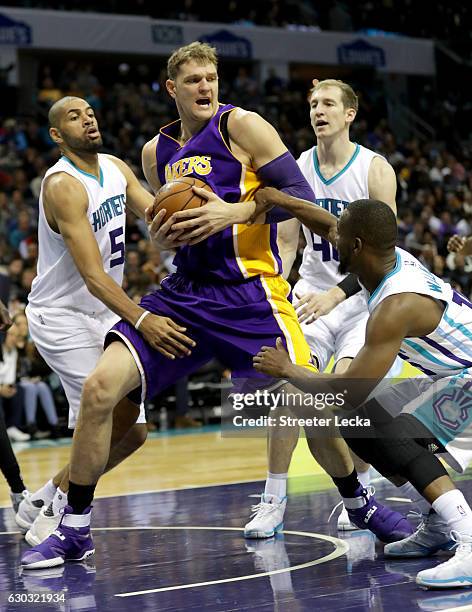 Timofey Mozgov of the Los Angeles Lakers tries to keep the ball away from teammates Nicolas Batum and Kemba Walker of the Charlotte Hornets during...