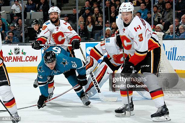 Kevin Labanc of the San Jose Sharks is checked by Deryk Engelland of the Calgary Flames as Jyrki Jokipakka and Chad Johnson of the Calgary Flames...