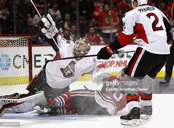 Mike Condon of the Ottawa Senators makes a save off of his gloves as Marcus Kruger of the Chicago Blackhawks crashes into him after being shoved down...