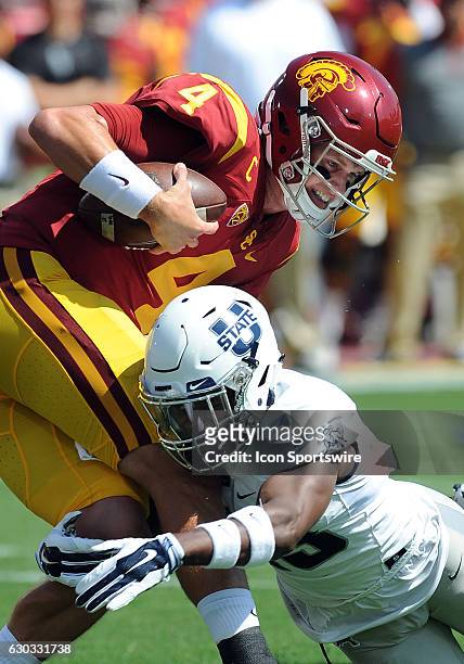 Trojans quarterback Max Browne runs with the ball and is tackled in the first quarter by Utah State Aggies cornerback Jalen Davis in a game played at...
