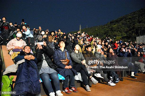 People look up sky as the Epsilon-2 rocket carrying Exploration of energization and Radiation in Geospace satellite lifts off from the launch pad at...