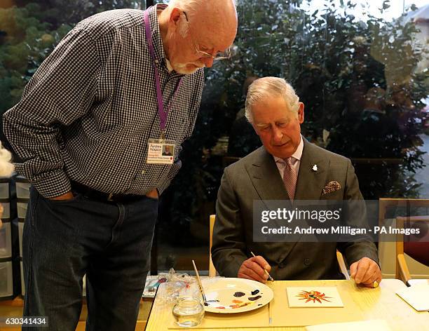 Prince Charles standing-volunteer occupational therapist George Bell taking part in a painting class during his visit to the Ayrshire Hospice in Ayr...