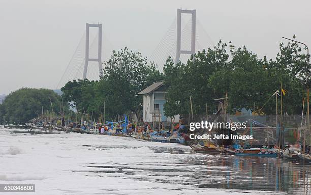 Fishermen seen repairing their nets in the polluted Tambak Wedi river on December 21, 2016 in Surabaya, Indonesia. These pictures show the...