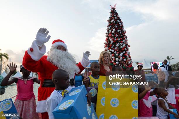 Man dressed as Santa Claus poses with Ivory Coast's first lady Dominique Ouattara and children at the presidential palace in Abidjan on December 21,...