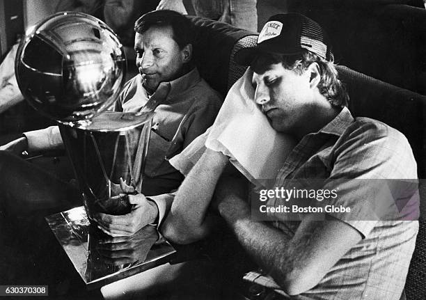 Boston Celtics player Larry Bird, right, sleeps on the plane back to Boston from Houston, as Celtics trainer Ray Melchiorre, left, holds the NBA...