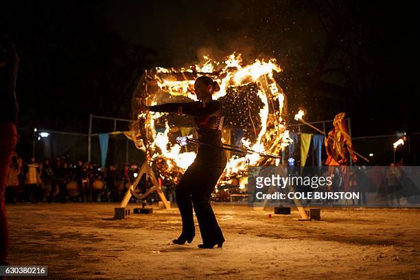 Performer spins a burning hula hoop as she takes part in the 27th Annual Kensington Market Winter Solstice Parade in Toronto on December 21, 2016. /...