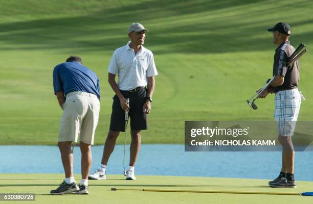 President Barack Obama waits to putt on the 18th green with friends Darell Harrington and Bobby Titcomb at the Kapolei Golf Club in Kapolei on...