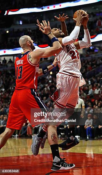 Taj Gibson of the Chicago Bulls goes up for a shot between Marcin Gortat and John Wall of the Washington Wizards at the United Center on December 21,...