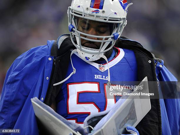 Linebacker Jerry Hughes of the Buffalo Bills reads a playsheet as he walks along the sideline during a game against the Cleveland Browns on December...