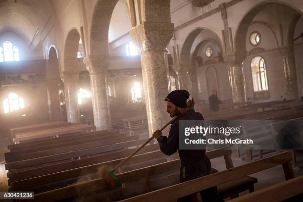 Man sweeps dust off seating in preparation for the Christmas Day mass at the Mar Hanna Church on December 22, 2016 in Mosul, Iraq. After recently...
