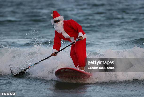 Roray Kam dressed as Santa Claus enjoys the surf on his standup paddle board on December 22, 2016 in Fort Lauderdale, Florida. South Florida is...