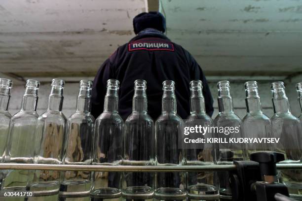 Picture taken on November 25, 2016 shows a policeman as he stands inside of an illicit vodka distillery in the village of Kuchki outside Moscow. In a...