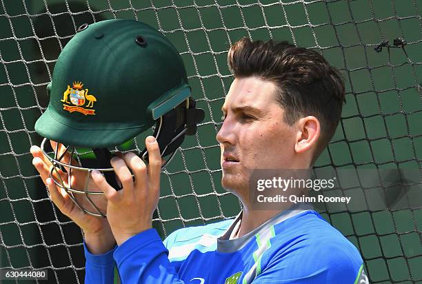 Nic Maddinson of Australia puts on his helmet before batting in the nets during an Australian training session on December 23, 2016 in Melbourne,...