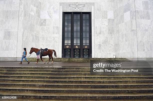 Demonstrator walks with a horse as she prepares to take part in a rally outside the Oregon State Capitol to honor LaVoy Finicum, who was killed by...