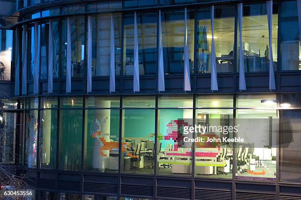 Father Christmas in his sleigh being pulled by Rudolph the Red Nose Reindeer is created from Post-it notes and displayed on an office window in...
