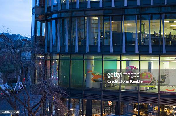 Father Christmas in his sleigh being pulled by Rudolph the Red Nose Reindeer is created from Post-it notes and displayed on an office window in...