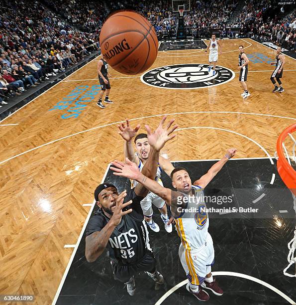 Stephen Curry and Klay Thompson of the Golden State Warriors go up for a rebound against Trevor Booker of the Brooklyn Nets on December 22, 2016 at...