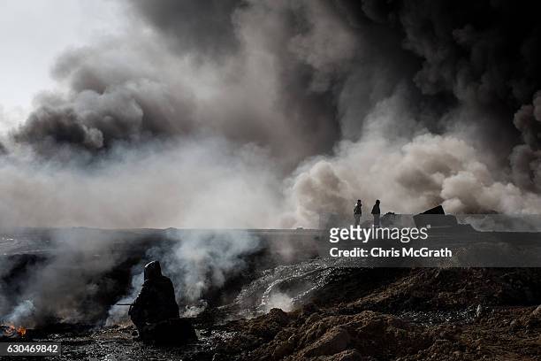 Member of the Federal police watches on as officials from an oil company inspect the blaze on December 23, 2016 in Qayyarah, Iraq. The fire crews,...