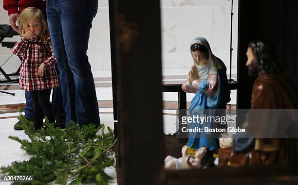 Two and a half year old Aria Scully of Grafton looks over at a privately funded Nativity Scene inside the Great Hall at the State House in Boston on...