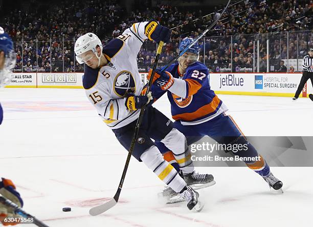 Jack Eichel of the Buffalo Sabres is checked by Anders Lee of the New York Islanders during the first period at the Barclays Center on December 23,...