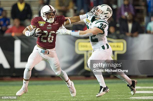 Running back B.J. Smith of the Troy Trojans stiff arms linebacker Quentin Poling of the Ohio Bobcats on December 23, 2016 in Mobile, Alabama.