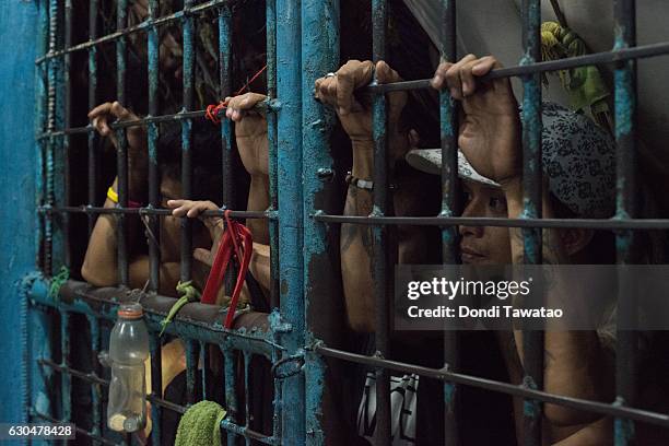 Inmates look outside from an overcrowded jail cell inside a police precint jail on December 15, 2016 in Manila, Philippines. Philippine president...