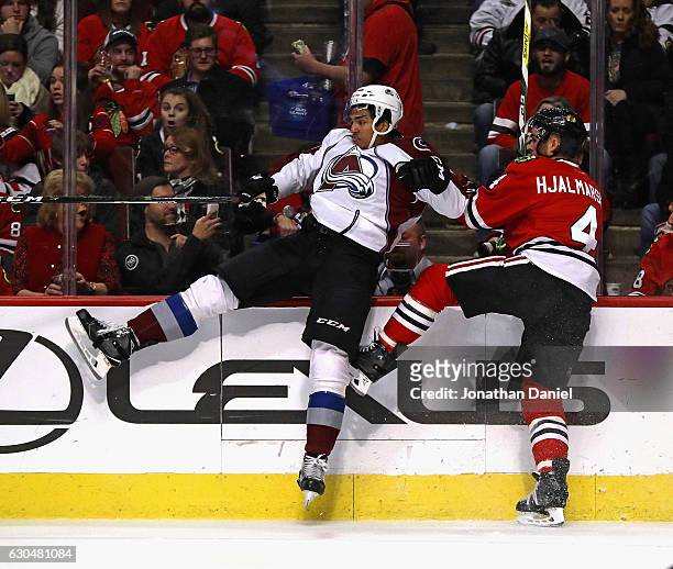 Andreas Martinsen of the Colorado Avalanche and Niklas Hjalmarsson of the Chicago Blackhawks hit the boards after colliding at the United Center on...
