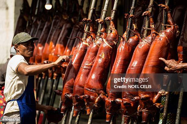 Worker removes hair from roasted pigs for sale along a street in Manila on December 24, 2016. "Lechon", or roasted pig, is a regular fare at...