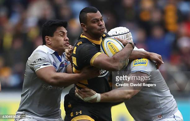 Kurtley Beale of Wasps is held by Ben Tapuai and Dave Attwood during the Aviva Premiership match between Wasps and Bath Rugby at The Ricoh Arena on...