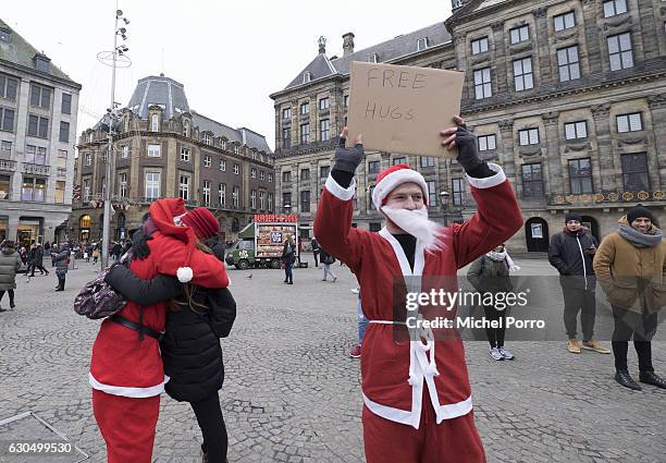 Santas give free hugs on Christmas eve to visitors and tourists on Dam Square on December 24, 2016 in Amsterdam, The Netherlands. Passers by were...