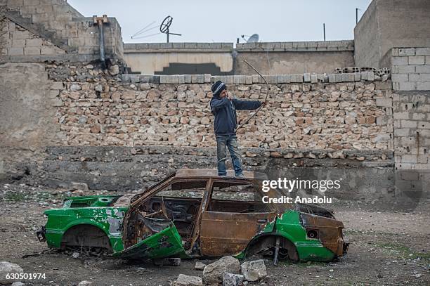 Syrian kid aims with his arrow over a wreckage of a car as Syrians live freely against all odds in Jarabulus after its cleansing of Daesh militants...