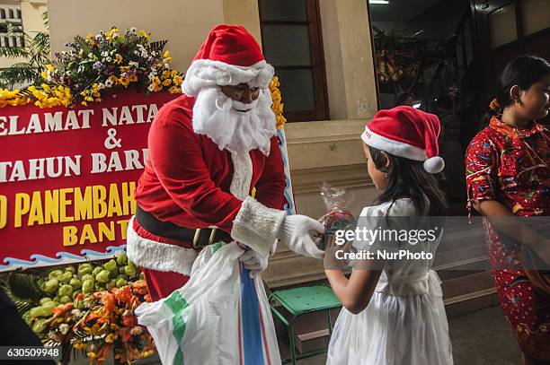 Santa Claus giving gifts to a child when attend mass in celebration of Christmas in Sacred Heart of Jesus Catholic Church in Yogyakarta, Indonesia,...