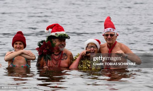 Members of the Berliner Seehunde swimming club with Father Christmas outfits pose for a picture during their traditional Christmas swimming on...