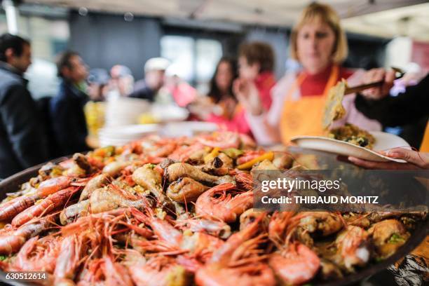 Volunteers serve paella to people on December 25 in Bordeaux, southwestern France, during a Christmas event organised by the local restaurant Bodega...