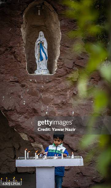 Christian child lights candles in front the statue of virgin Marry in the Holy Family Catholic Church during Christmas on December 25, 2016 in...