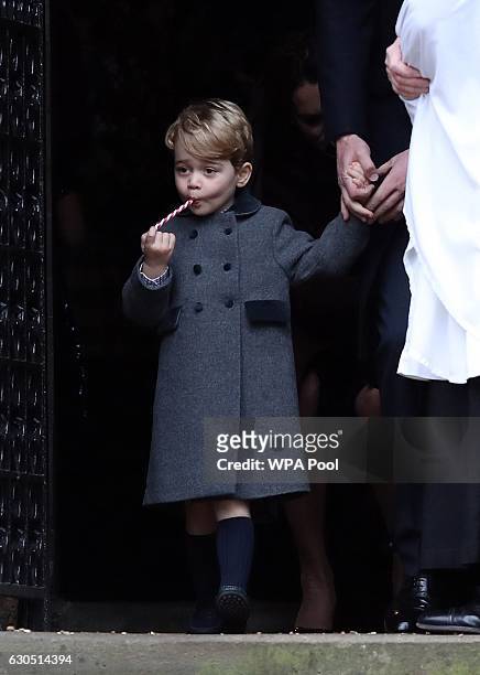 Prince George of Cambridge eats a sweet as he leaves following the service at St Mark's Church on Christmas Day on December 25, 2016 in Bucklebury,...