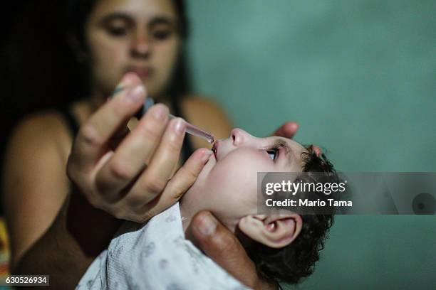 Mother Raquel Barbosa give medication to her daughter Eloisa, who has a twin sister named Eloa, both 8 months old and both born with microcephaly, on...