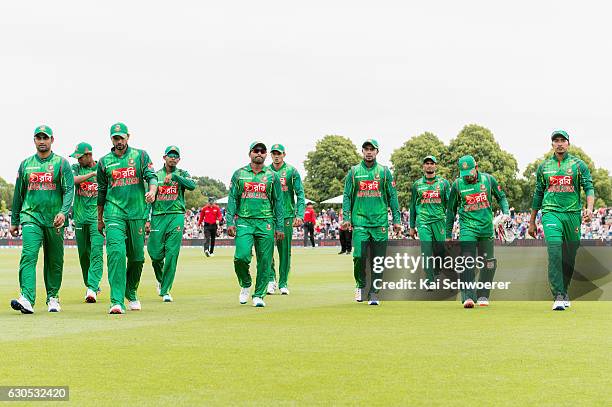 Imrul Kayes of Bangladesh and his team mates walk from the ground at the lunch break during the first One Day International match between New Zealand...